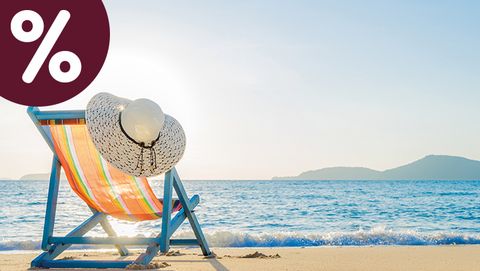 Gestreifter Liegestuhl mit Sonnenhut an einem hellen Sandstrand vor blauem Meer – Symbolbild für den sole uno Monats-Hit „Ein Tag am Meer“.