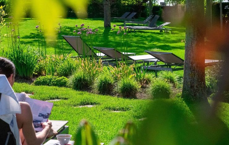 Frau liest auf Liegestuhl auf Liegewiese