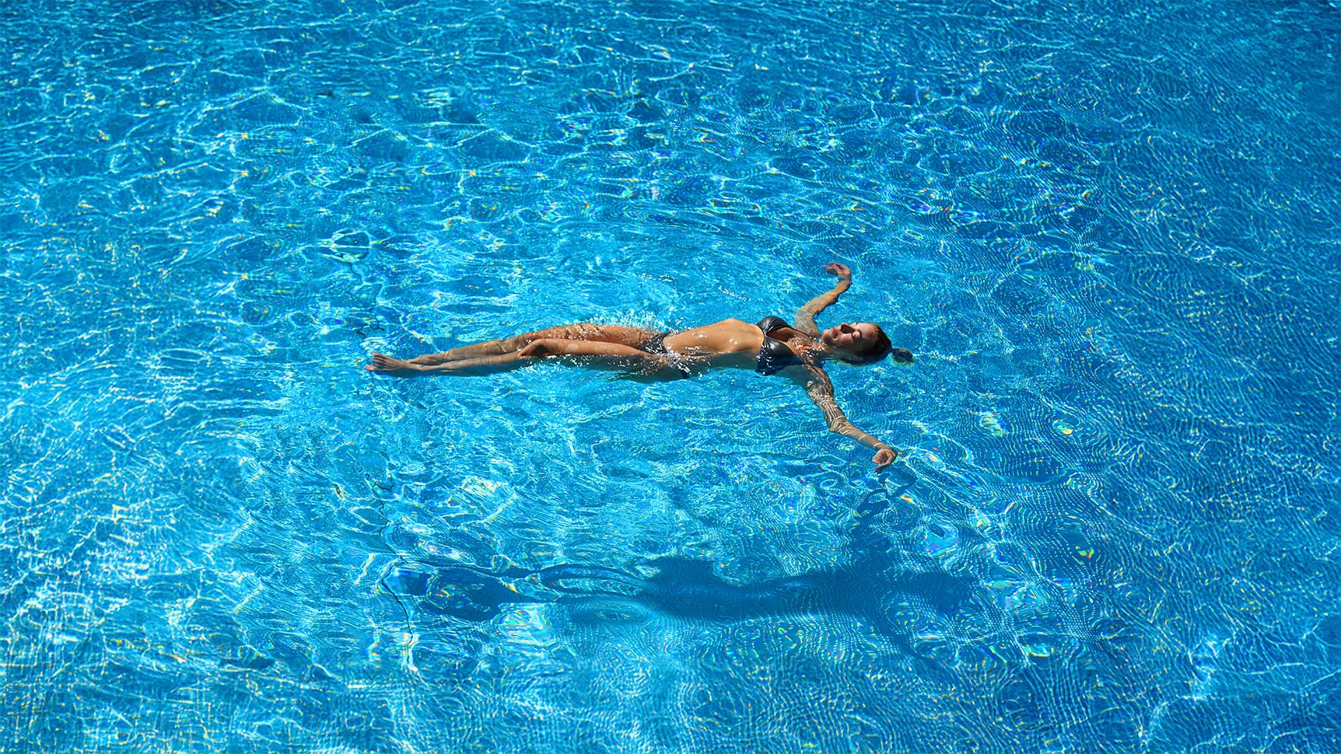 Eine Frau entspannt im Sommer beim Floating im tiefblauen, klaren Wasser im sole uno Rheinfelden.